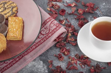 White cup of hot black tea with dried flower buds placed on a dark grey background . High quality photo