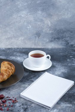 Mermer bir arka planda boş bir defter ile beyaz bir fincan sıcak çay. Yüksek kalite fotoğraf