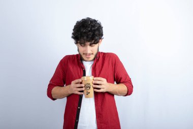 Beyaz duvarda mola vermek için elinde kahve tutan esmer adamın fotoğrafı. Yüksek kalite fotoğraf