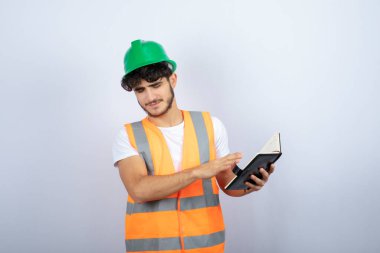 Yeşil şapkalı genç erkek mühendis defterde ne yazdığını bulmaya çalışıyor. Yüksek kalite fotoğraf