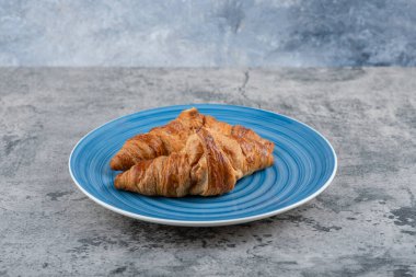 Taş yüzeyde mavi bir tabak taze çikolatalı kruvasan. Yüksek kalite fotoğraf