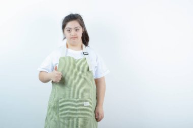 Kareli önlüklü genç güzel kız baş parmağını gösteriyor. Yüksek kalite fotoğraf