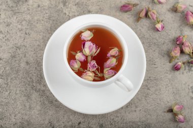 Taş yüzeyinde kurumuş güller olan bir fincan siyah çay. Yüksek kalite fotoğraf