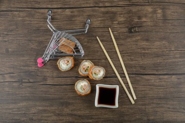 Soya soslu lezzetli suşi ruloları ve ahşap yüzeyde yemek çubukları. Yüksek kalite fotoğraf