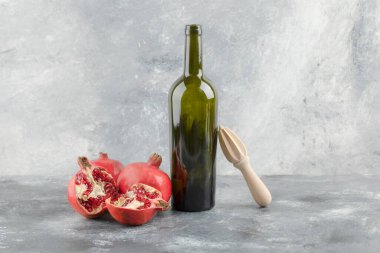 Mermer zemin üzerinde bir şişe şarap bulunan taze nar meyveleri. Yüksek kalite fotoğraf