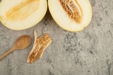 Ahşap kaşıkla mermer yüzeyde yarım lezzetli sarı kavunlar. Yüksek kalite fotoğraf