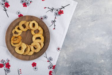 Beyaz masa örtüsünün üzerine kurumuş elma halkaları yerleştirilmiş tahta bir tabak. Yüksek kalite fotoğraf