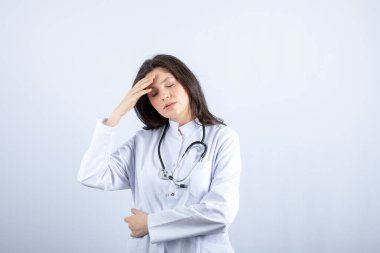 Young female doctor with stethoscope having headache on white background. High quality photo