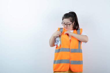 Gözlüklü güzel bayan mühendis üniformasını beyaz arka planda kontrol ediyor. Yüksek kalite fotoğraf