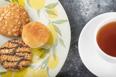 Tabakta tatlı abur cuburlar ve arka planda beyaz bir fincan çay. Yüksek kalite fotoğraf