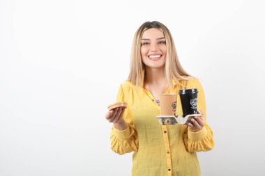 Gülümserken elinde kahve fincanları tutan genç bir kadın resmi. Yüksek kalite fotoğraf