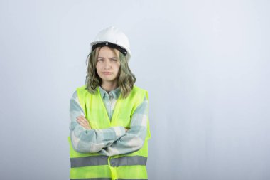 Beyaz fonda duran beyaz şapkalı genç inşaat işçisinin görüntüsü. Yüksek kalite fotoğraf