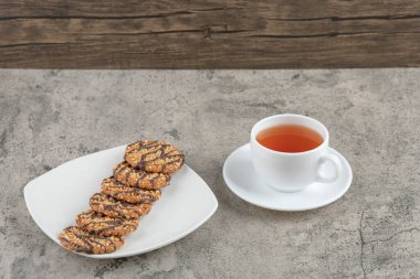 Taze pişmiş yulaflı kurabiyeler serpiştirilmiş tohumlar ve bir fincan siyah çay. Yüksek kalite fotoğraf