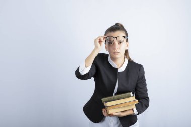 Gözlüklü bayan öğrencinin beyaz arka planda kitaplarla poz vermesi. Yüksek kalite fotoğraf