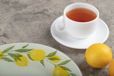 Cup of black tea with juicy lemons placed on marble table. High quality photo