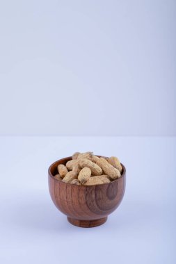 Beyaz arka planda soyulmamış fıstıklarla dolu ahşap bir kase. Yüksek kalite fotoğraf