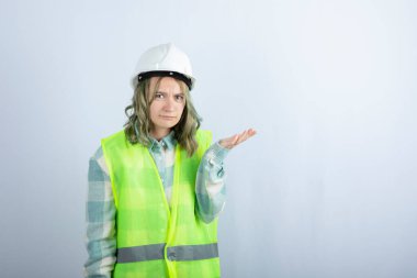 Beyaz fonda duran beyaz şapkalı genç inşaat işçisinin görüntüsü. Yüksek kalite fotoğraf