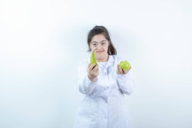 Doktor üniformalı genç bir kız elinde yeşil elmalı armut meyvesi tutuyor. Yüksek kalite fotoğraf