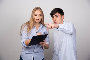 Gri arka planda bir projeyi tartışan iki genç ofis arkadaşı. Yüksek kalite fotoğraf