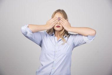 Yetişkin bir kadın, elleri gri arka planda olan gözleri kapatıyor. Yüksek kalite fotoğraf