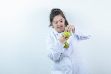 Doktor üniformalı genç bir kız elinde yeşil elmalı armut meyvesi tutuyor. Yüksek kalite fotoğraf