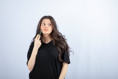 Beyaz arka planda fırçayla allık süren genç ve güzel bir model resmi. Yüksek kalite fotoğraf