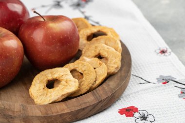 Ahşap bir tabak kırmızı elma ve masa örtüsünün üzerinde kurumuş halkalar. Yüksek kalite fotoğraf