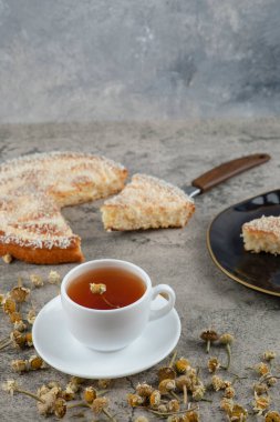 Lezzetli bir pastanın siyah tabağı ve arka planda beyaz bir fincan sıcak çay. Yüksek kalite fotoğraf