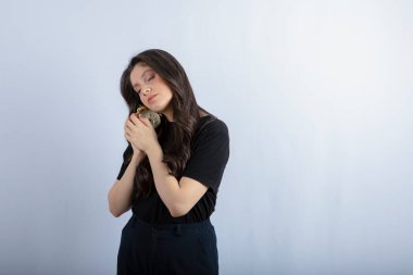 Beyaz arka planda uyuyan çalar saati olan genç bir kız resmi. Yüksek kalite fotoğraf