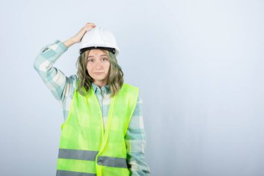 Beyaz fonda duran beyaz şapkalı genç inşaat işçisinin görüntüsü. Yüksek kalite fotoğraf