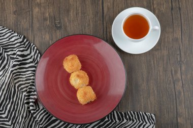 Kırmızı tabak lezzetli kadaif hamur işleri ve tahta masada bir fincan çay. Yüksek kalite fotoğraf