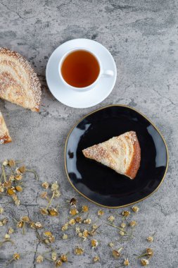 Lezzetli bir parça kek ve beyaz bir fincan sıcak çay ile siyah bir tabak. Yüksek kalite fotoğraf