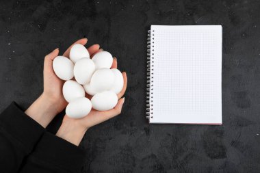 Siyah arka planda bir avuç çiğ yumurtayı tutan kadın eli. Yüksek kalite fotoğraf