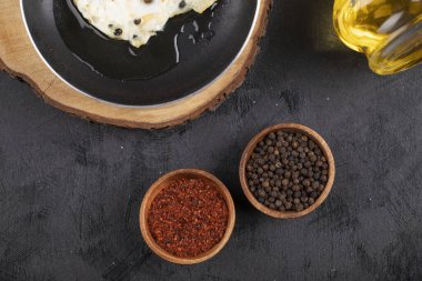 Güneşli tarafı tavada yumurta kızartma, baharatlar ve siyah yüzeyde bir şişe yağ. Yüksek kalite fotoğraf