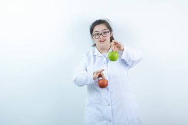 Doktor üniformalı genç bir kız elinde yeşil ve kırmızı elma meyveleri tutuyor. Yüksek kalite fotoğraf