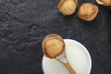 Siyah arka planda kaşık ve ceviz kurabiyeli bir fincan süt. Yüksek kalite fotoğraf