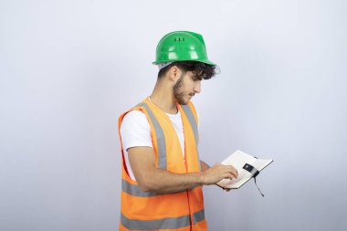 Yeşil şapkalı genç mühendis beyaz arka planda notlar okuyor. Yüksek kalite fotoğraf