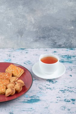 Kraker ve bir fincan çayla birlikte konsantre sütle birlikte kırmızı bir tabak kurabiye. Yüksek kalite fotoğraf