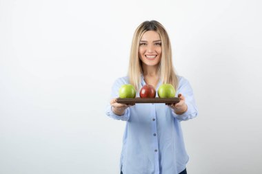 Beyazın üzerinde duran bir tabak elmalı genç sarışın kadın portresi. Yüksek kalite fotoğraf