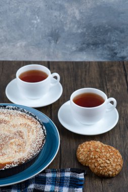 Tahta masaya konmuş turta ve çayla yerleştirilmiş tahıllı yulaf ezmeli kurabiyeler. Yüksek kalite fotoğraf