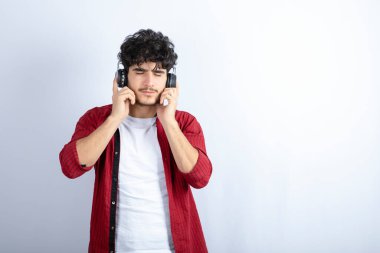Kulaklıklı genç bir adamın beyaz arka planda duruşu. Yüksek kalite fotoğraf