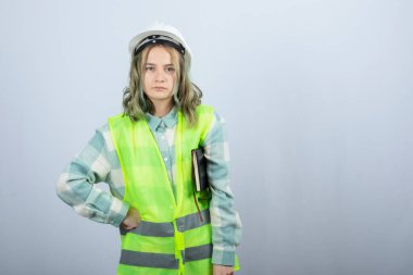 Not defteriyle beyaz duvarda poz veren güzel bir kadın mühendis resmi. Yüksek kalite fotoğraf