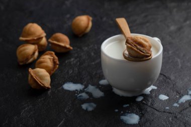 Siyah arka planda ahşap kaşık cevizli kurabiye ile bir fincan süt. Yüksek kalite fotoğraf