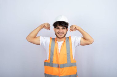 Beyaz kasklı yakışıklı genç adam beyaz duvarın üzerinde kameraya poz veriyor. Yüksek kalite fotoğraf