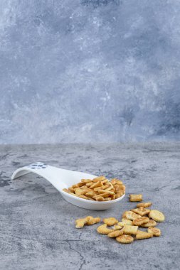 Beyaz seramik kaşık mermer zemin üzerinde tuzlanmış krakerlerle dolu. Yüksek kalite fotoğraf