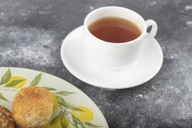 Tabakta tatlı abur cuburlar ve arka planda beyaz bir fincan çay. Yüksek kalite fotoğraf