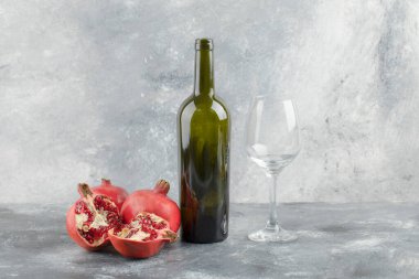 Mermer zemin üzerinde bir şişe şarap bulunan taze nar meyveleri. Yüksek kalite fotoğraf