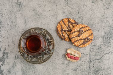 Bir bardak siyah çay, lezzetli bisküviler, çikolata ve mermer yüzeyde tohumlar. Yüksek kalite fotoğraf