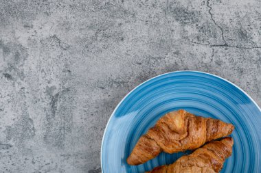 Taş yüzeyde mavi bir tabak taze çikolatalı kruvasan. Yüksek kalite fotoğraf