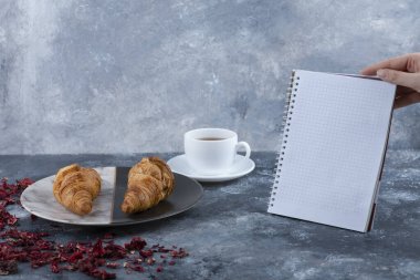 Dişi el ele tutuşması, ayçöreği olan bir fincan çayın yanında bir defter açtı. Yüksek kalite fotoğraf